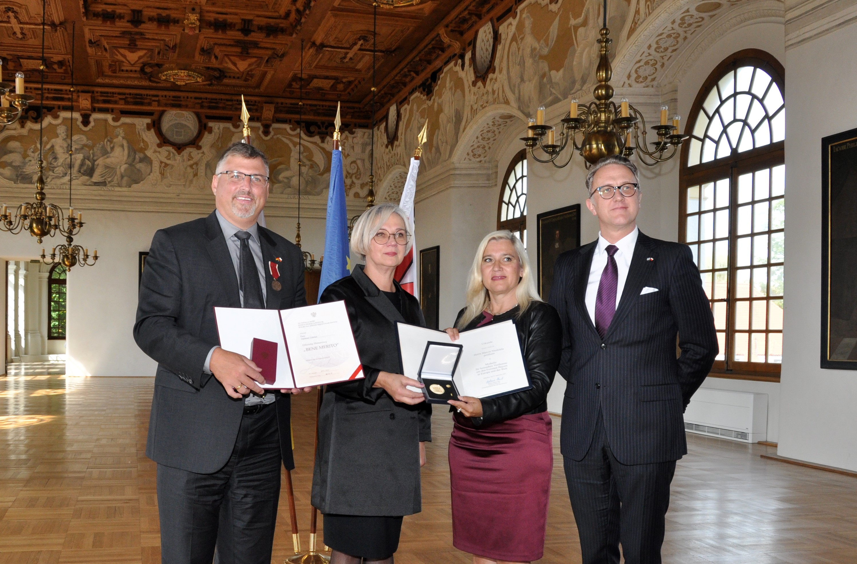 Übergabe der Ehrungen im Dachauer Schloss
Personen von links Landrat Stefan Löwl mit dem Bene Merito Orden, Dorota Niedziela, Ehefrau des verstorbenen Landrats Marcin Niedziela mit der Europa Medaille, Melanie Huml, Bayerische Europaministerin und Jan M. Malkiewicz, polnischen Generalkonsul