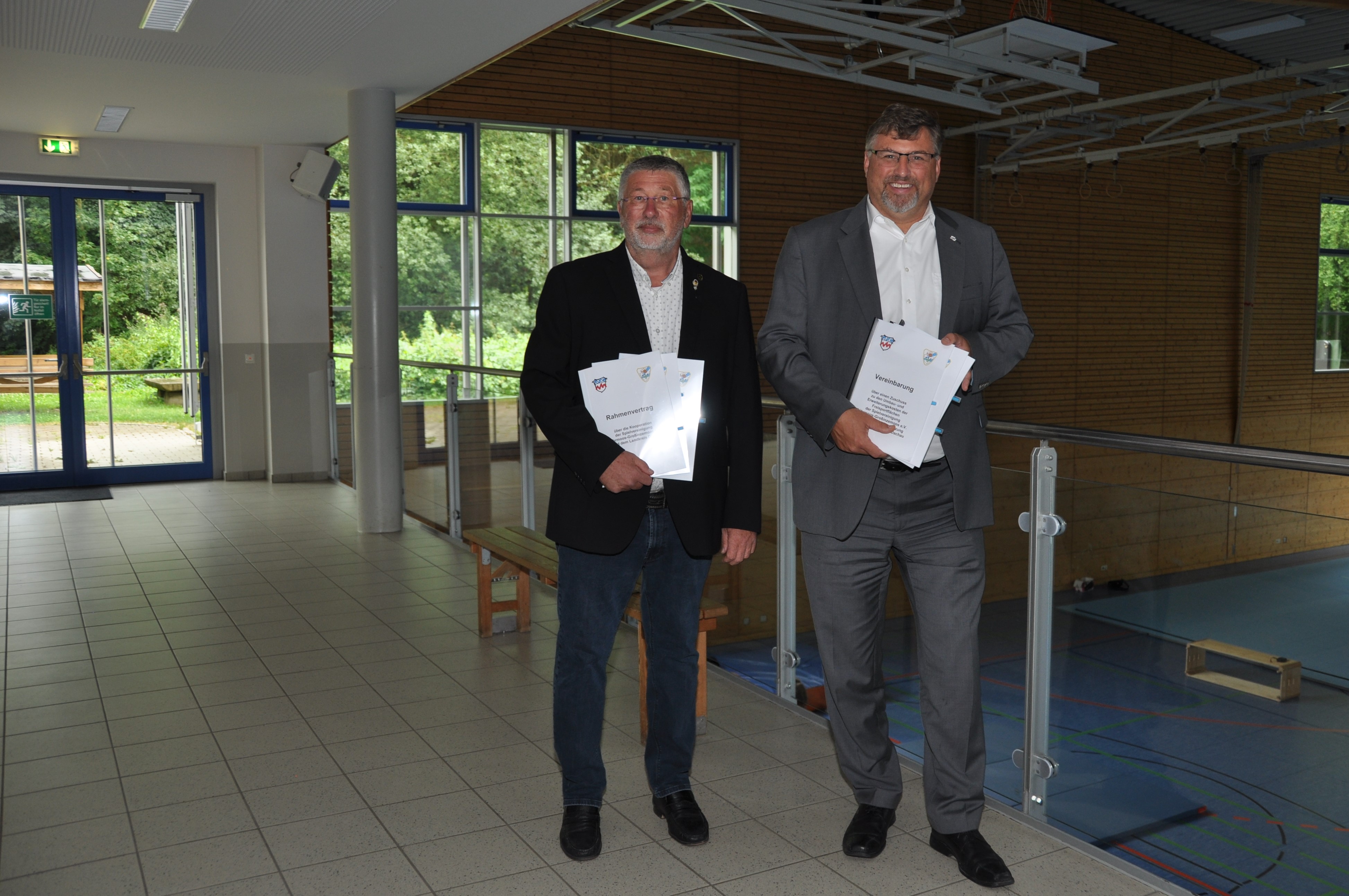 Landrat Stefan Löwl und Günter Bakomenko Vorsitzender der Spielvereinigung Röhrmoos-Großinzemoos mit den Vertragsunterlagen in der Sporthalle
