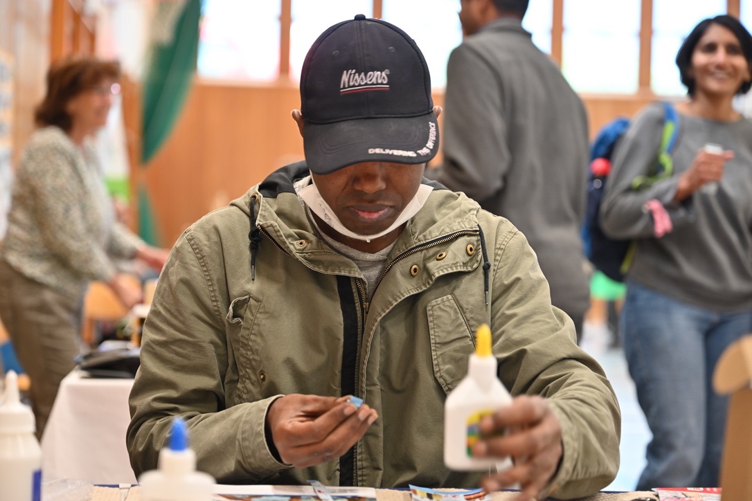 Herr Diallo zeigt wie man nur mit Kleber und Papier Handtaschen kunstvoll gestalten kann.