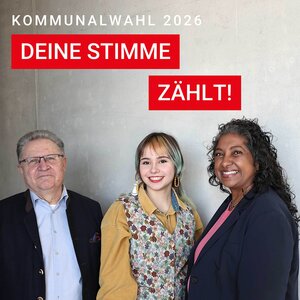 Bild vergr&ouml;&szlig;ern: Das Bild zeigt drei Personen unterschiedlichen Alters, die nebeneinander vor einer hellgrauen Wand stehen und in die Kamera lächeln. Links steht ein älterer Mann mit Brille, dunklem Sakko und hellem Hemd. In der Mitte steht eine junge Frau mit schulterlangen Haaren, die eine gemusterte Weste über einer gelben Bluse trägt. Rechts steht eine erwachsene Frau mit lockigem Haar, dunklem Blazer und rosafarbenem Oberteil.

Im oberen Bildbereich steht der Text „Kommunalwahl 2026“. In roten Textfeldern sind die Worte „Deine Stimme“ und „zählt!“ zu lesen. Das Motiv vermittelt Vielfalt und soll zur Teilnahme an der Kommunalwahl 2026 ermutigen.