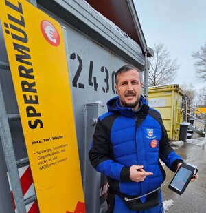 Bild vergr&ouml;&szlig;ern: Ein Mann steht vor einem Sperrmüllcontainer und hat ein Kassengerät um mit EC Karte zu zahlen