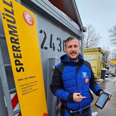 Bild vergr&ouml;&szlig;ern: Ein Mann steht vor einem Sperrmüllcontainer und hat ein Kassengerät um mit EC Karte zu zahlen