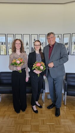 Frauke Meister und Ines Steinwinter stehen zusammen mit Landrat Löwl in seinem Büro