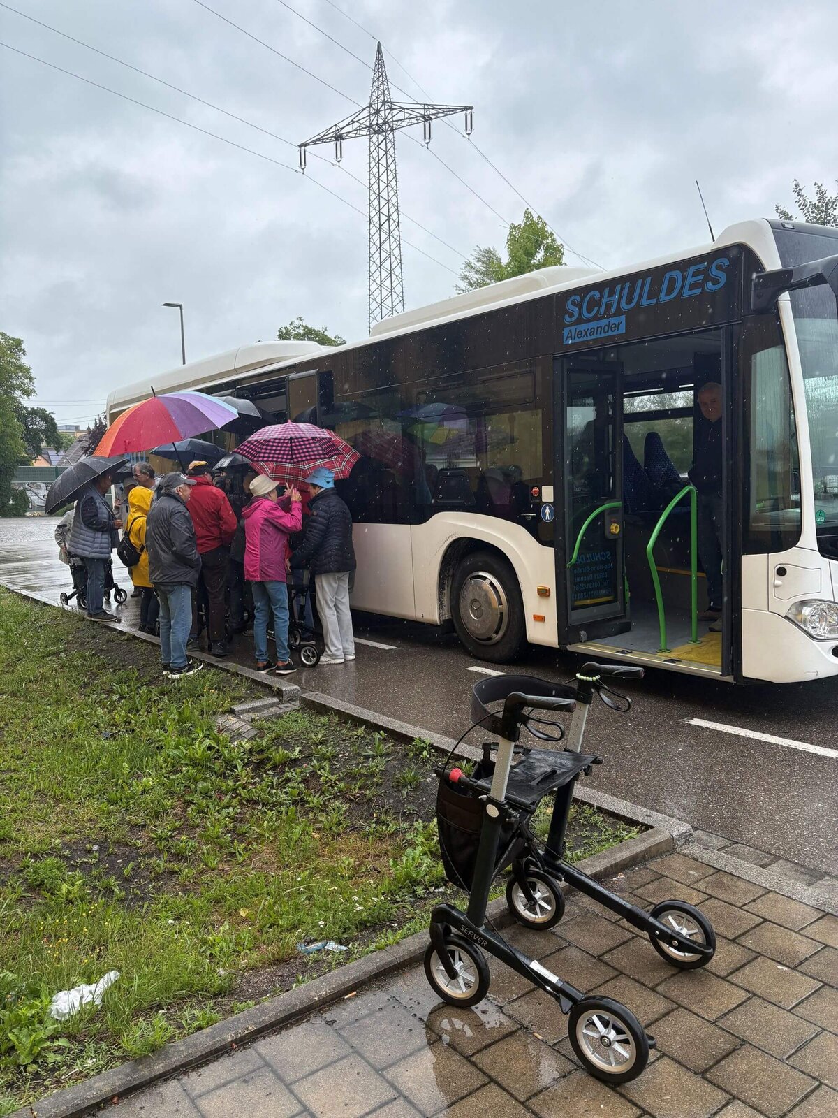 Eine Gruppe Senioren trainieren im Regen das Ein- udn Aussteigen in einen Linienbus