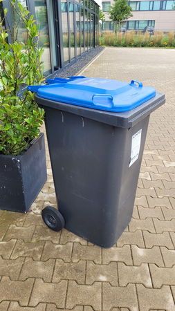 Eine blaue Abfalltonne steht vor einem Gebäude