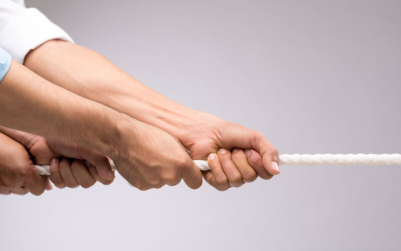 Hände, die gemeinsam an einem Seil  ziehen