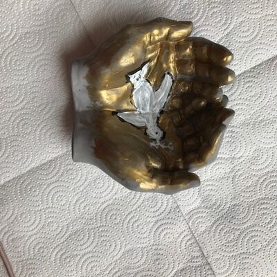 Bild vergr&ouml;&szlig;ern: Geöffnete Hände in Gold mit Friedenssymbol