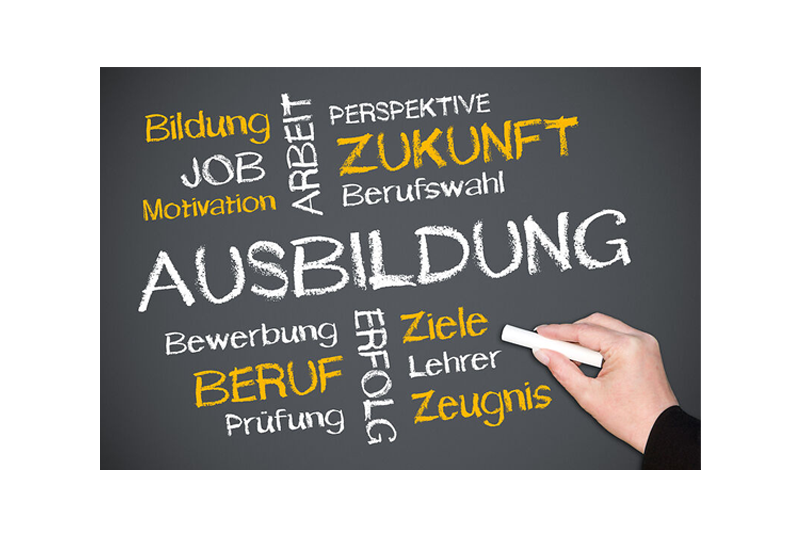 Schief dargestellte Tafel mit Worten zur Ausbildung, darunter groß „AUSBILDUNG“ und kleinere Wörter wie Bildung Job Motivation Arbeit Perspektive Zukunft Beruf Prüfung Erfolg Ziele Zeugnis Bewerbung Lehrer, eine Hand schreibt mit Kreide rechts.