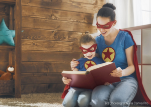Mutter liest mit Kind im Superheldenkostüm ein Buch