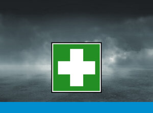 Ein weißes Kreuz auf grünem Hintergrund vor einem wolkenverhangenen, dunklen Himmel.