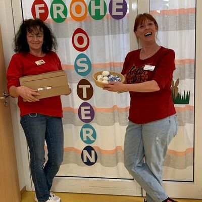 Bild vergr&ouml;&szlig;ern: Zwei Mitarbeiterinnen übergeben die Osterbasteleien